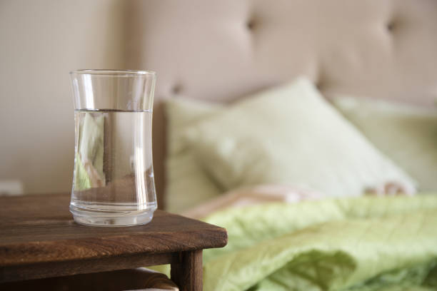 Neatly arranged nightstand with a glass of water and folded blanket